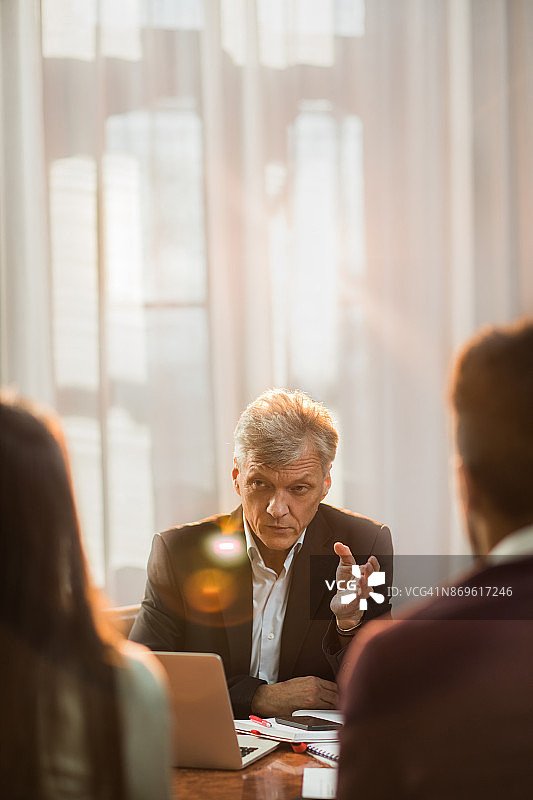 年长的保险代理人在他的办公室里与一对夫妇交流图片素材