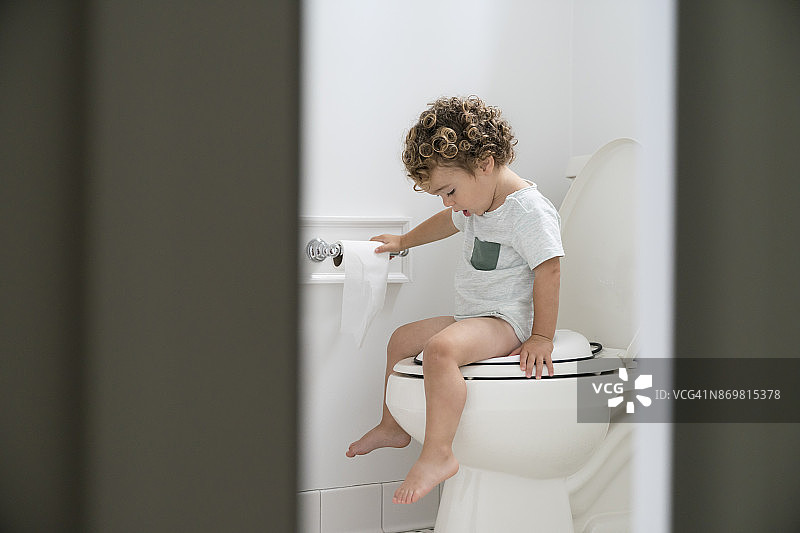 进行如厕训练的男童坐在马桶上图片素材
