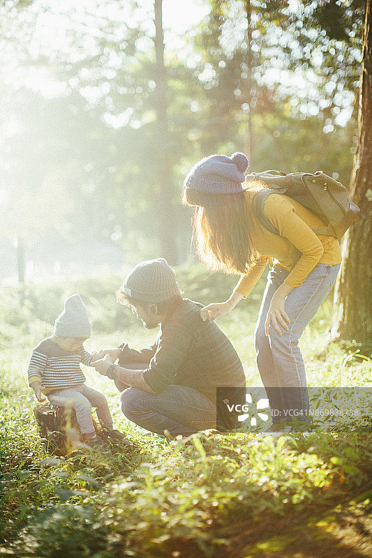 坐在木材上的亚洲男婴和他的家人在森林里图片素材