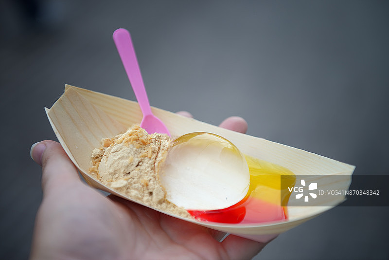 手持日式水信玄饼配彩色糖浆和黄豆粉图片素材