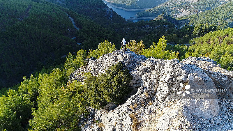 站在岩石山坡上的山地自行车骑手图片素材