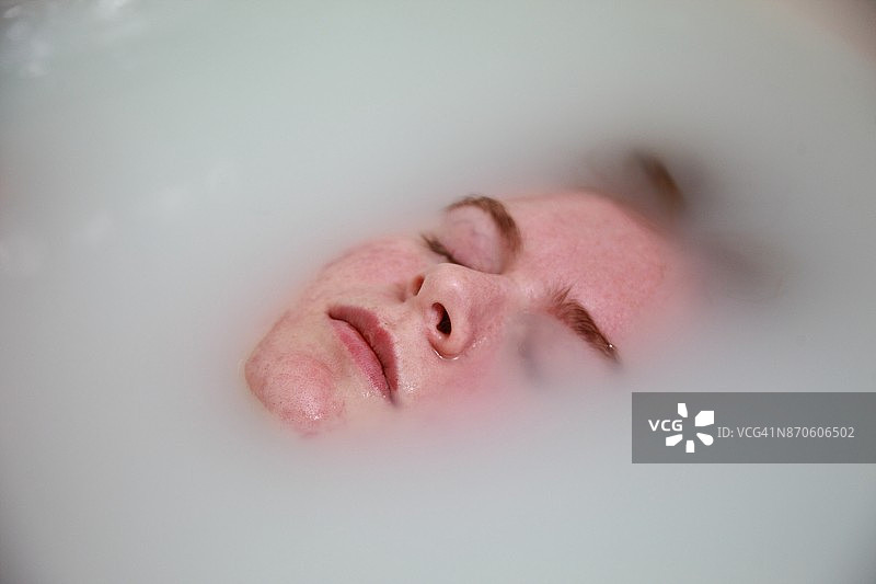 年轻女子在牛奶浴中放松身心图片素材