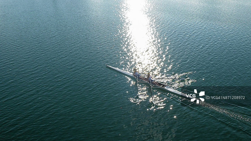 两名女运动员在阳光下于湖上划船图片素材