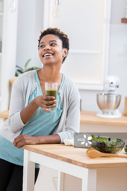 年轻女人在厨房享用蔬菜汁图片素材
