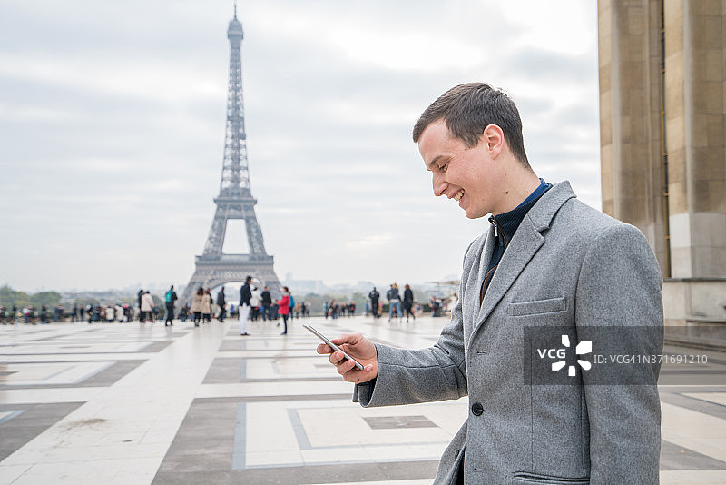在巴黎埃菲尔铁塔下使用智能手机的商人图片素材