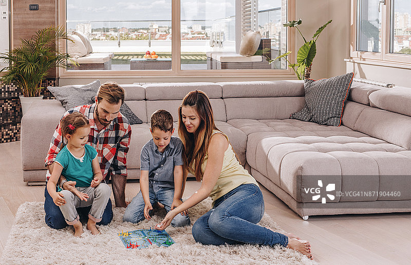 年轻家庭在顶层公寓地毯上玩游戏图片素材