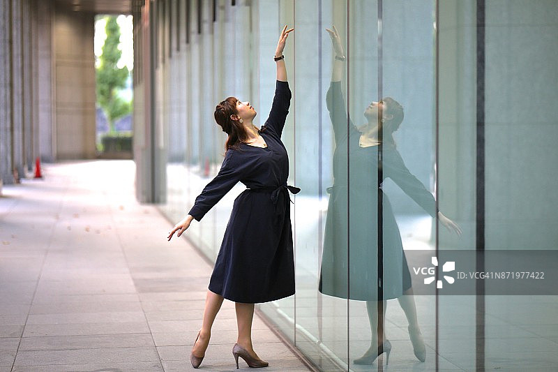 年轻女子在建筑物的镜子前跳舞图片素材