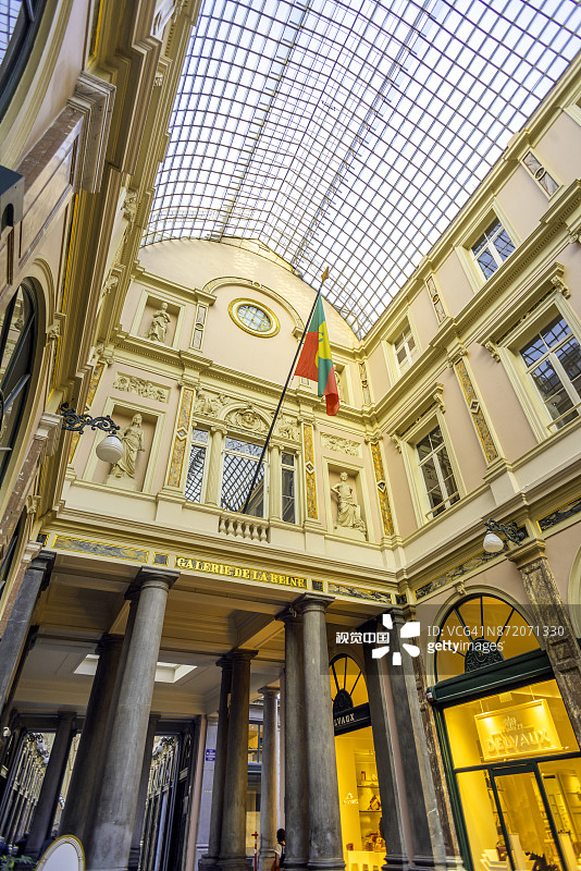 游客和购物者在比利时布鲁塞尔圣休伯特皇家拱廊街玻璃屋顶下漫步的竖版图图片素材