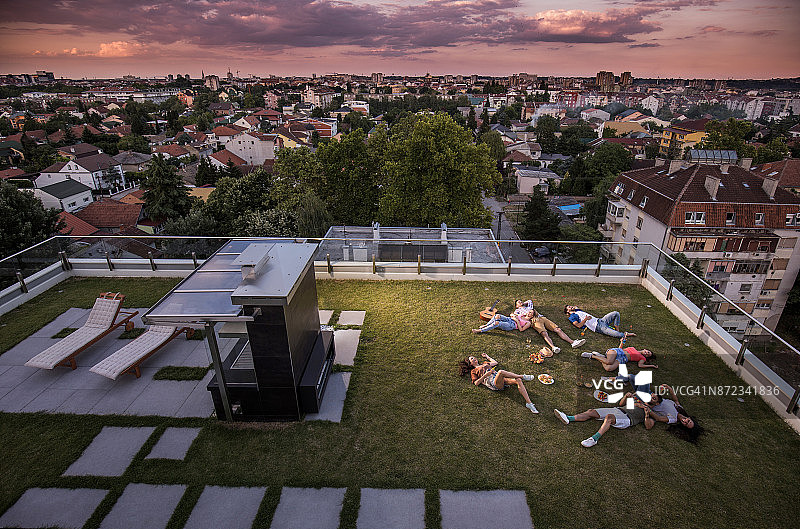 在顶层露台草地上放松的年轻人的俯视图图片素材
