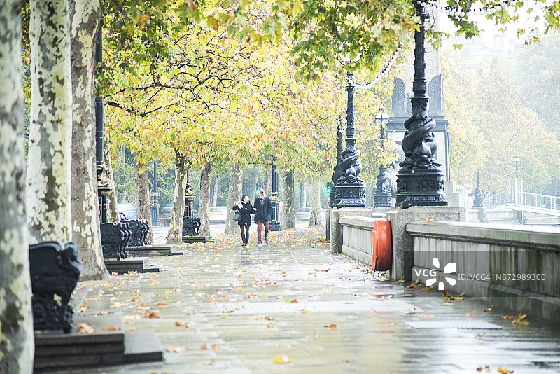 情侣在泰晤士河堤岸冒雨行走图片素材