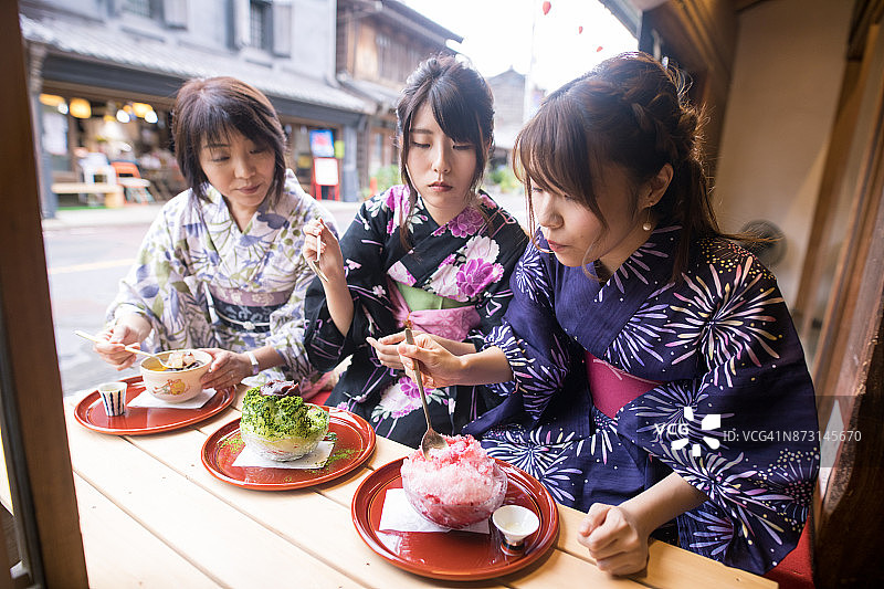 母亲和女儿穿着浴衣在户外咖啡馆吃刨冰图片素材