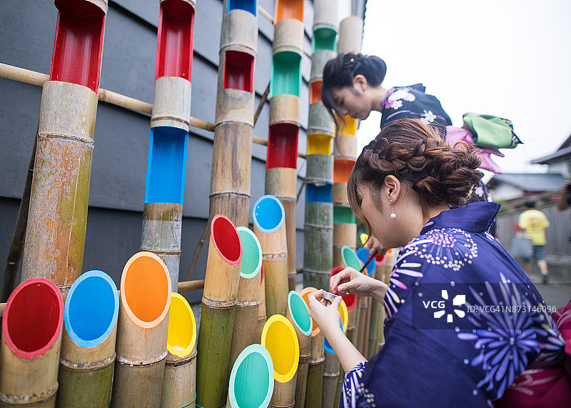 穿着浴衣的姐妹们在为夜间活动准备竹子装饰图片素材
