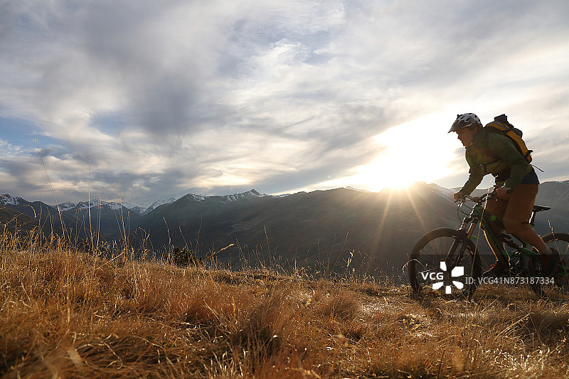 山地自行车手攀登山脊，日落时分图片素材