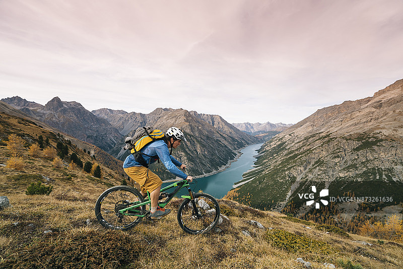 山地自行车骑行者登上山脊，下方是山谷图片素材