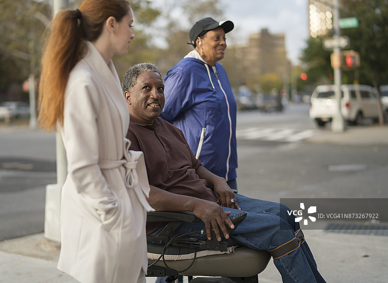 在街上，白人少女和坐轮椅的非洲裔男人和女人交谈图片素材