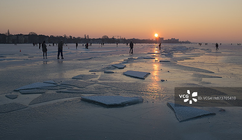 日落时分的冰面和滑冰者图片素材