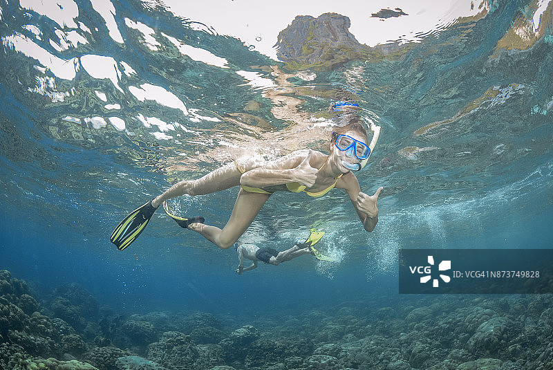 女子在珊瑚礁上浮潜并点赞图片素材