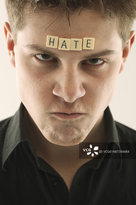 头上放着拼字块拼成“hate”字样的男人图片素材