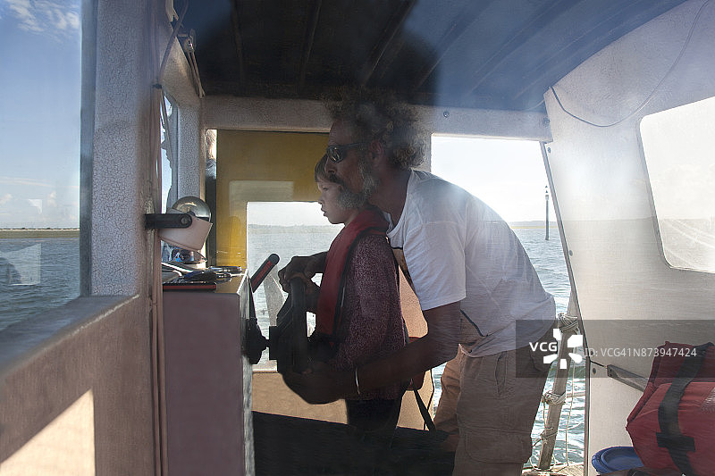 男孩和一名男子一起驾驶船图片素材