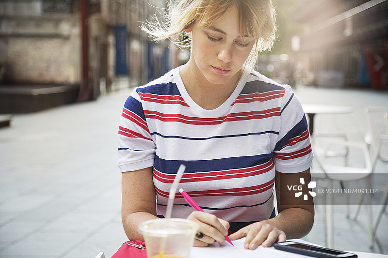 女人坐在城市广场的户外咖啡馆里写作图片素材