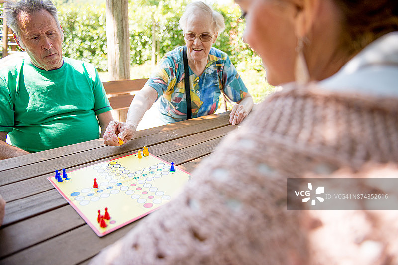 与女性看护一起玩飞行棋的老年妇女图片素材