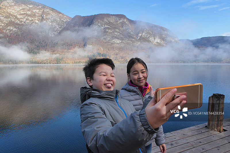 兄妹在湖边做鬼脸自拍图片素材