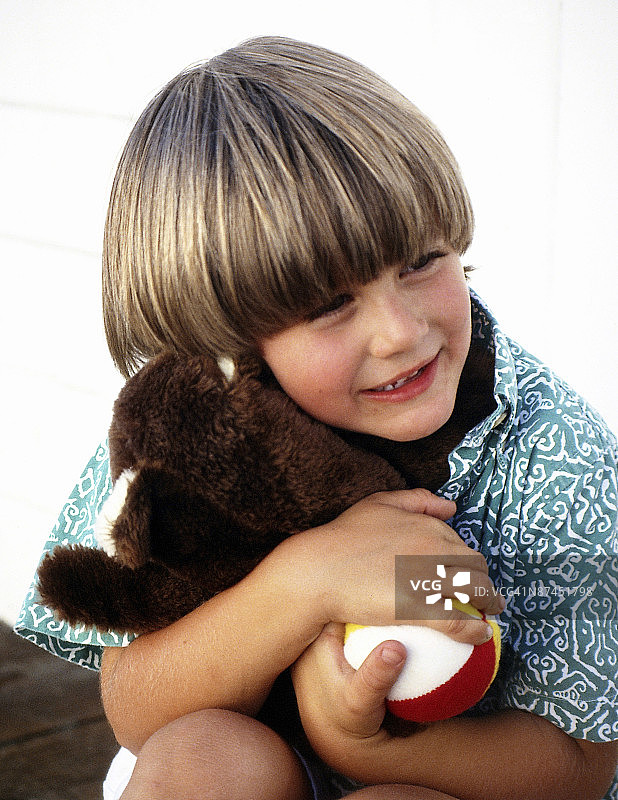 男孩拥抱泰迪熊和球图片素材