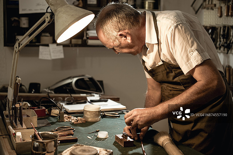 在车间修理小提琴的老年工匠图片素材