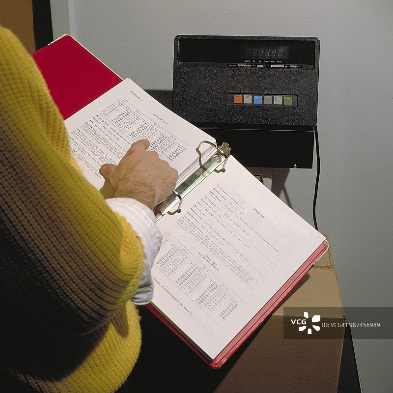 在体重秤前看手册的人图片素材