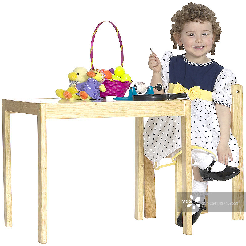 女孩坐在桌旁，手拿复活节篮子图片素材