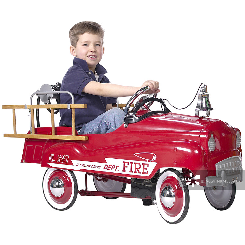 男孩坐在玩具消防车里图片素材