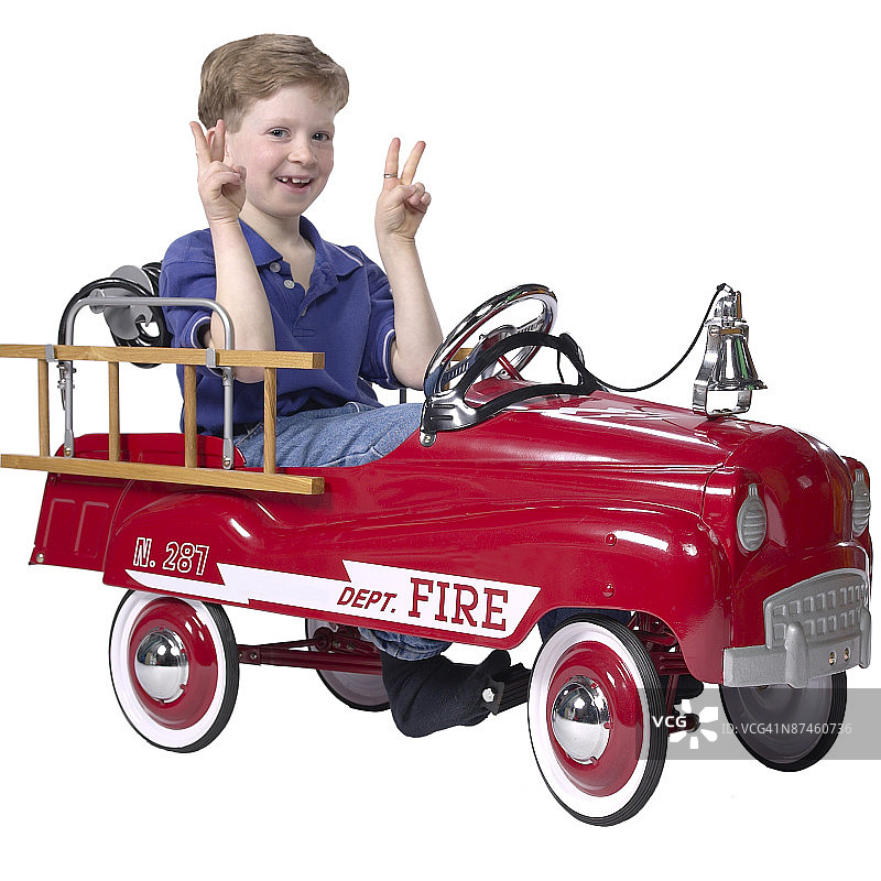 男孩坐在玩具消防车里图片素材