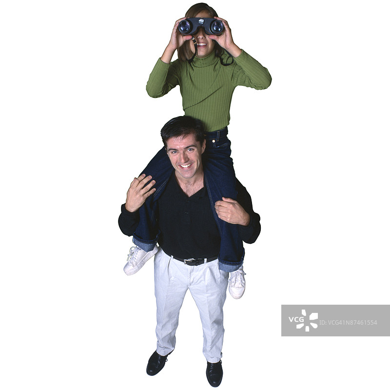 女孩坐在父亲的肩膀上用望远镜观察图片素材