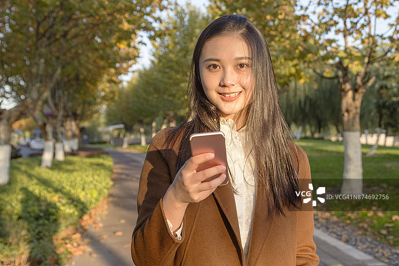 在公园使用手机的年轻女人图片素材