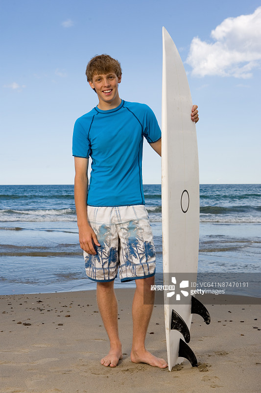 在海滩上带着冲浪板的微笑男人图片素材