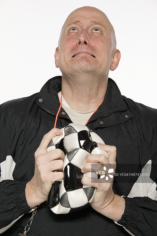 拿着漏气的足球的沮丧男人图片素材