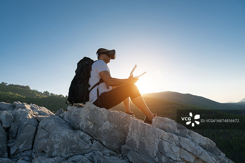 徒步无人机飞行员戴FPV眼镜山间飞行图片素材