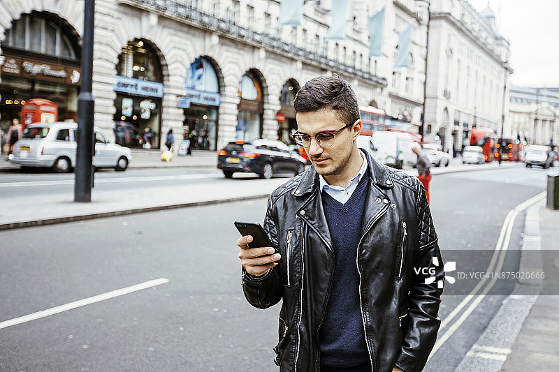 年轻男人在繁忙的街道上用手机阅读图片素材