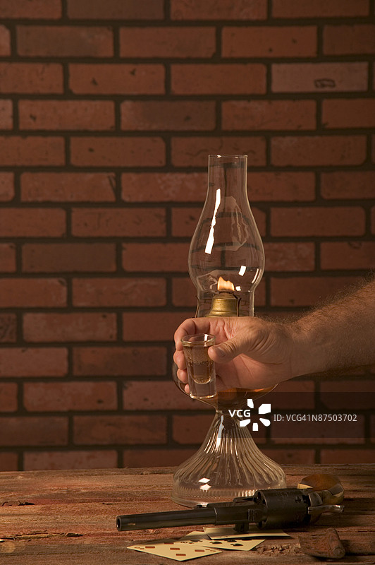 威士忌酒、扑克牌、油灯和左轮手枪的镜头图片素材