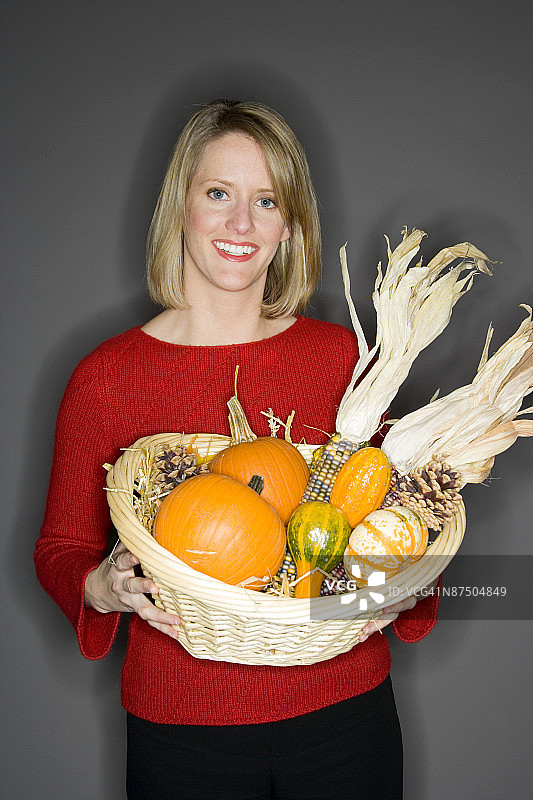 女人拿着装满秋季南瓜和玉米的篮子图片素材