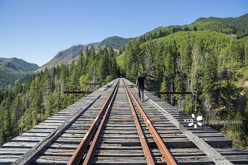 男人走在生锈的旧铁路桥上图片素材