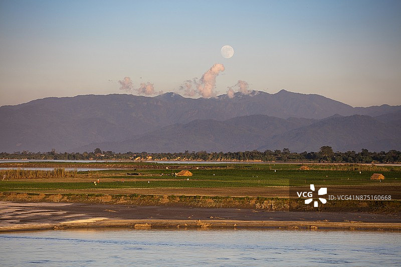 缅甸克钦邦八莫附近，伊洛瓦底江东岸的田野和棚屋，满月从山上升起图片素材