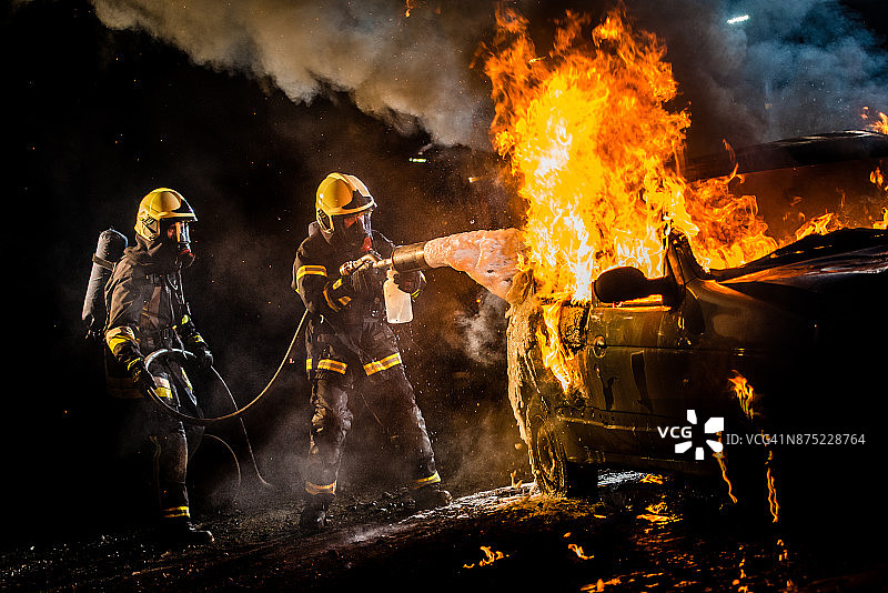 消防员向燃烧的汽车喷水图片素材