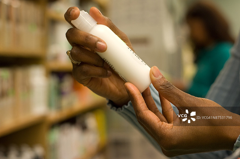 拿着瓶子并阅读标签的购物者图片素材