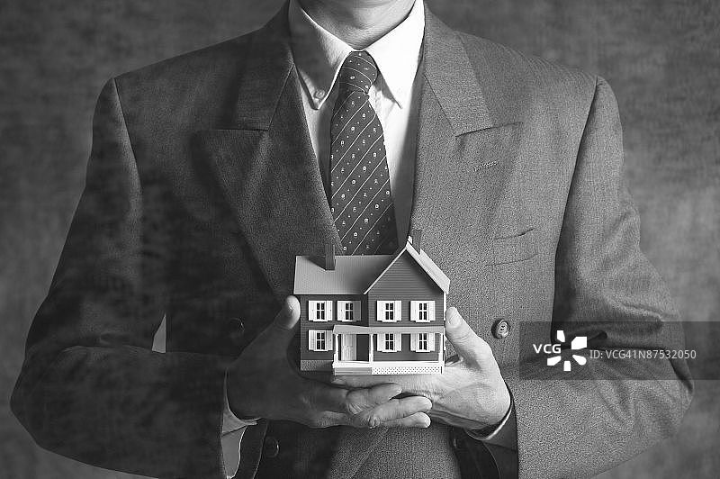 商人手持微型房屋图片素材