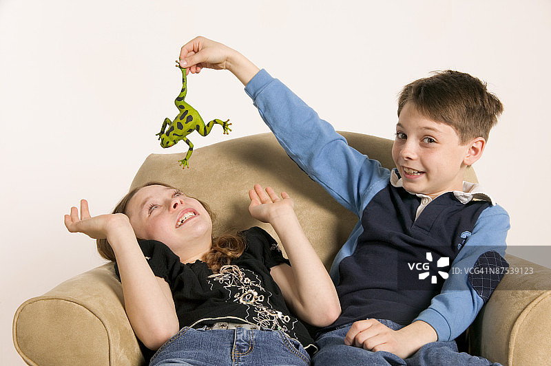 男孩用玩具青蛙吓唬女孩图片素材