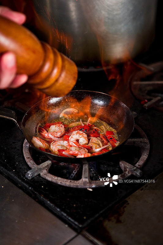 厨师在烤架上将胡椒粉撒在虾上图片素材