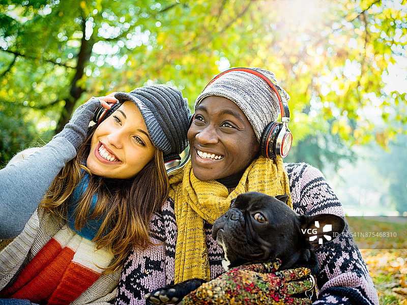 在公园里和狗玩耍的多元种族女性朋友图片素材