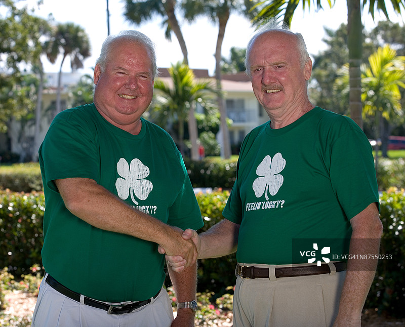 两名穿着相同衬衫的男子握手图片素材