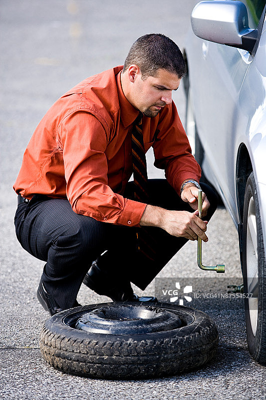 男子在停车场更换轮胎图片素材